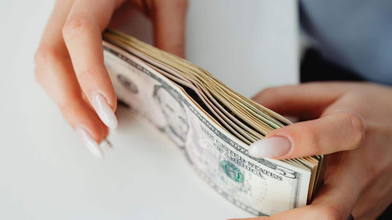 A pair of hands holding dollar bills.