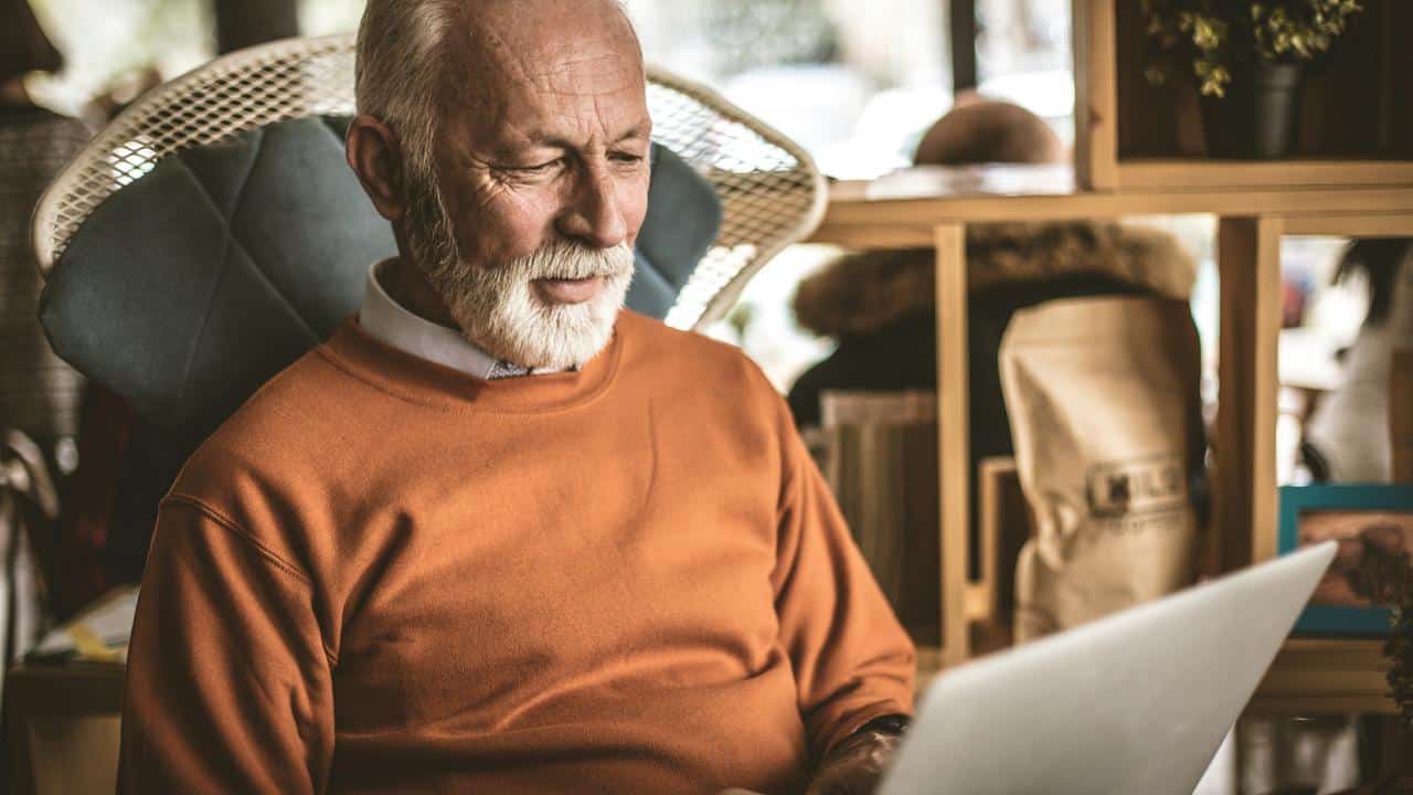 An older man using a laptop indoors.