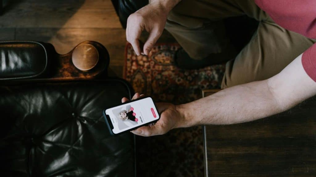 An overhead view of a person holding a smartphone displaying a dating profile for "Helen."