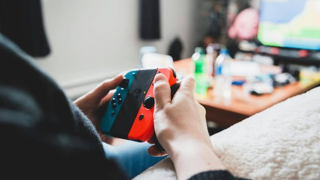 A person holding a controller and playing on a TV.