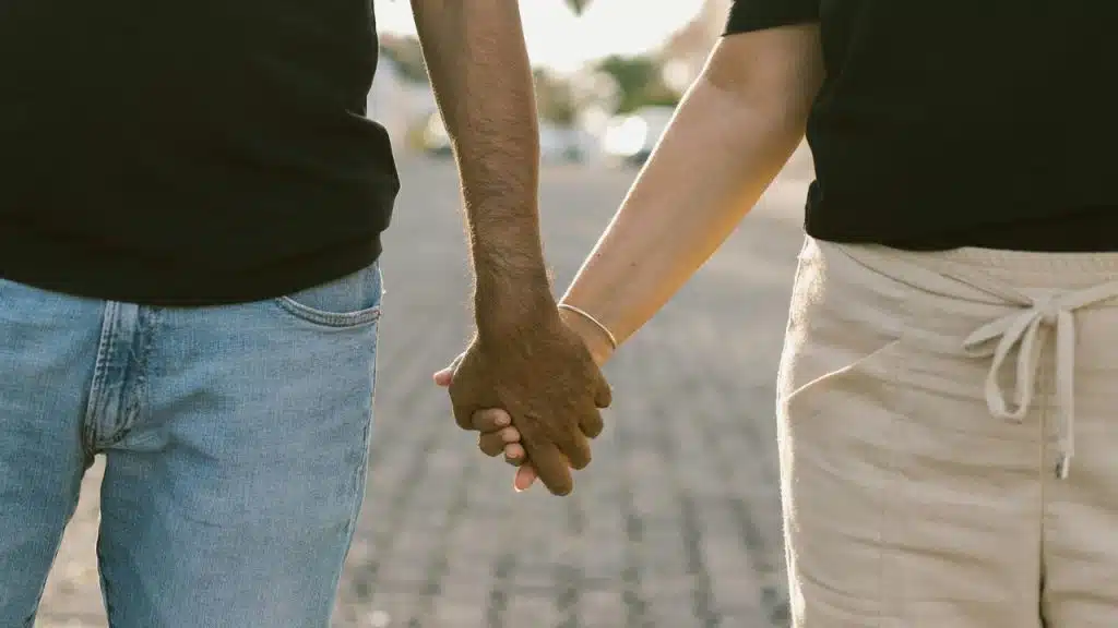 A couple holds hands while walking outdoors.