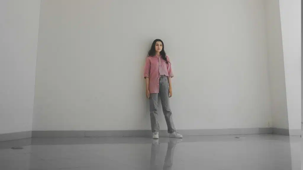 A woman standing in a room while leaning against a wall.