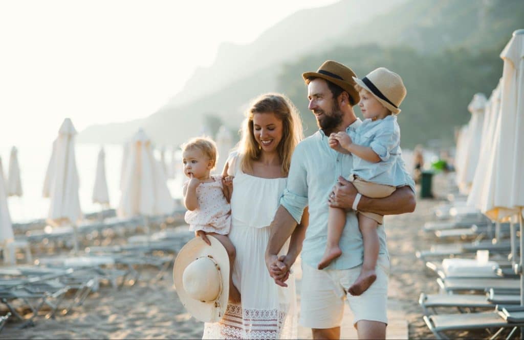 A man and woman carrying their children while walking