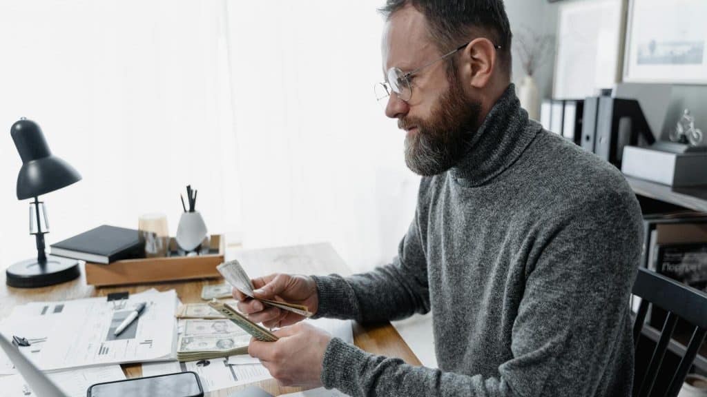 A man counting piles of dollar bills.