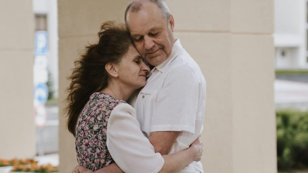 A mature couple shares a close embrace, looking peaceful and content.