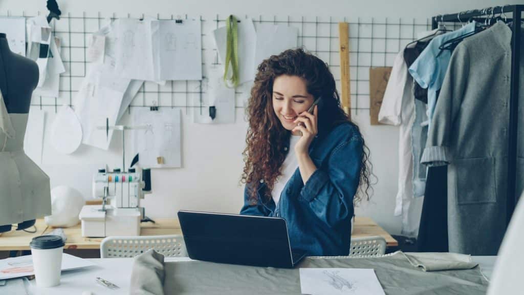 A fashion-designer-on-the-phone-working-on-a-laptop.