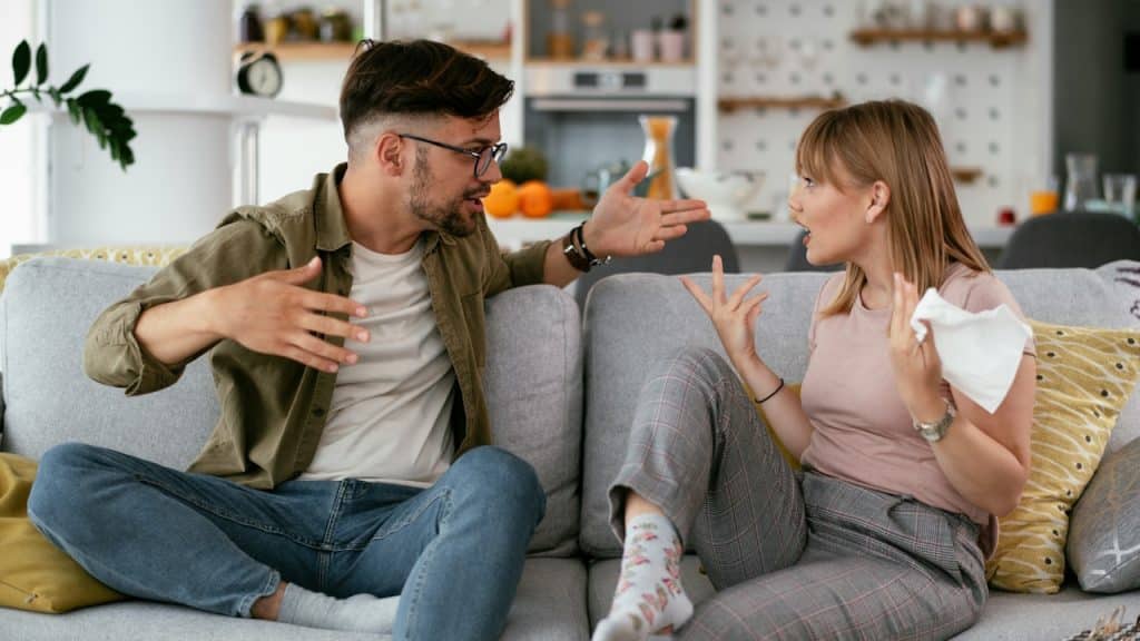 A couple arguing while sitting on a couch.