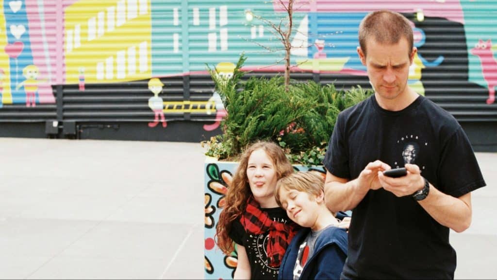 A man ignoring his kids behind him