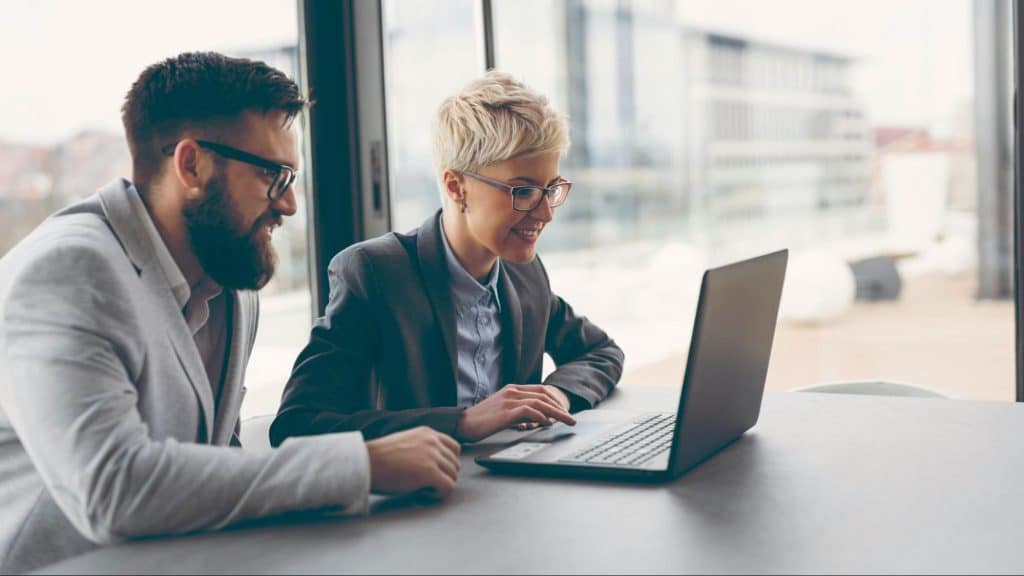 A man and woman looking at the laptop