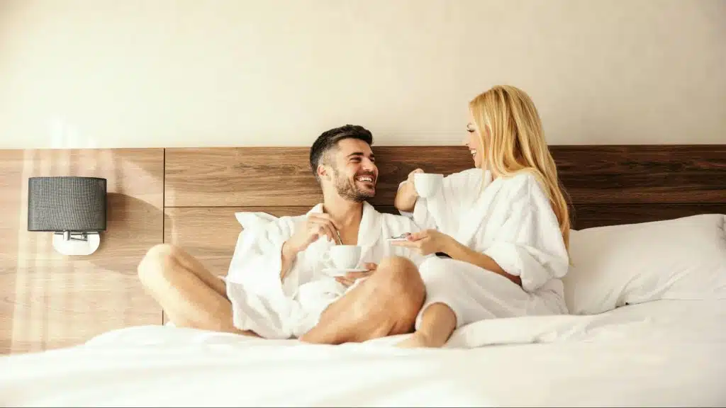 A man and woman talking while having coffee at the bed