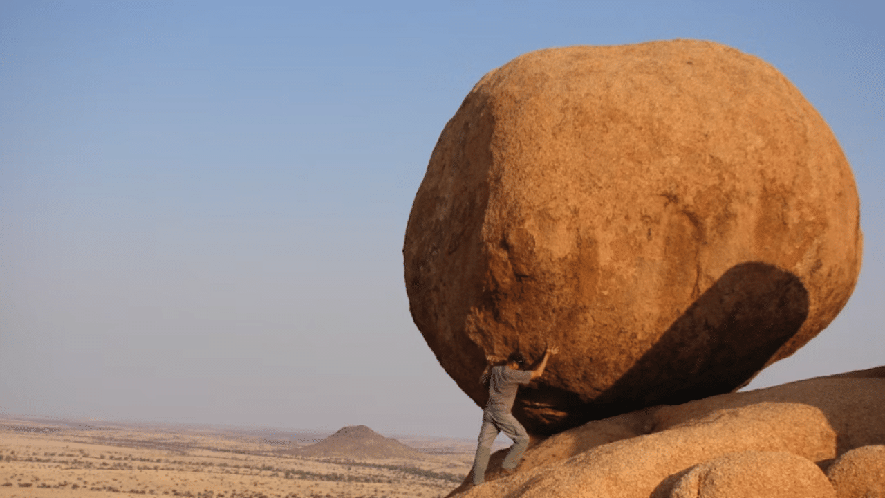 A man carrying a boulder up a hill