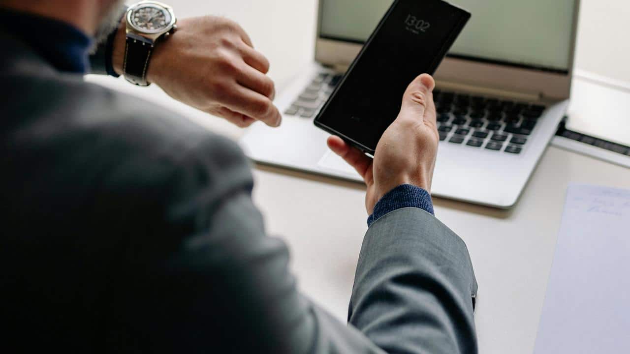 A person holding a phone and checking their watch.