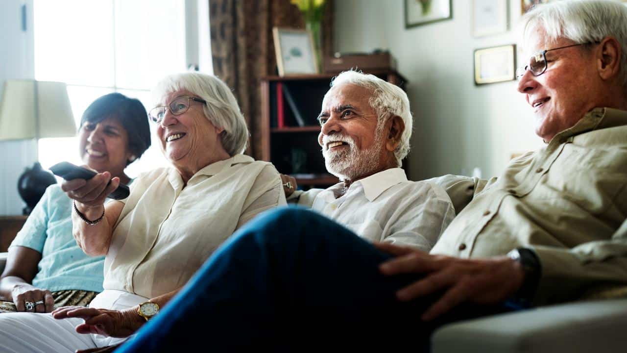A group of older adults watching TV together.