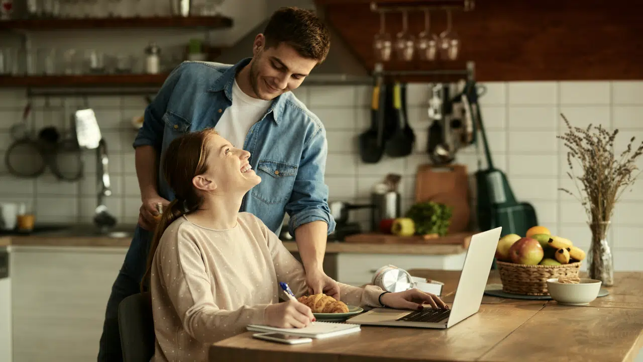 A man feeding his wife while she works