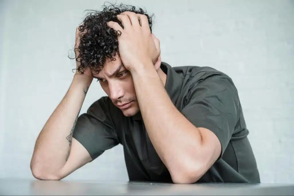 A man alone and holding his head