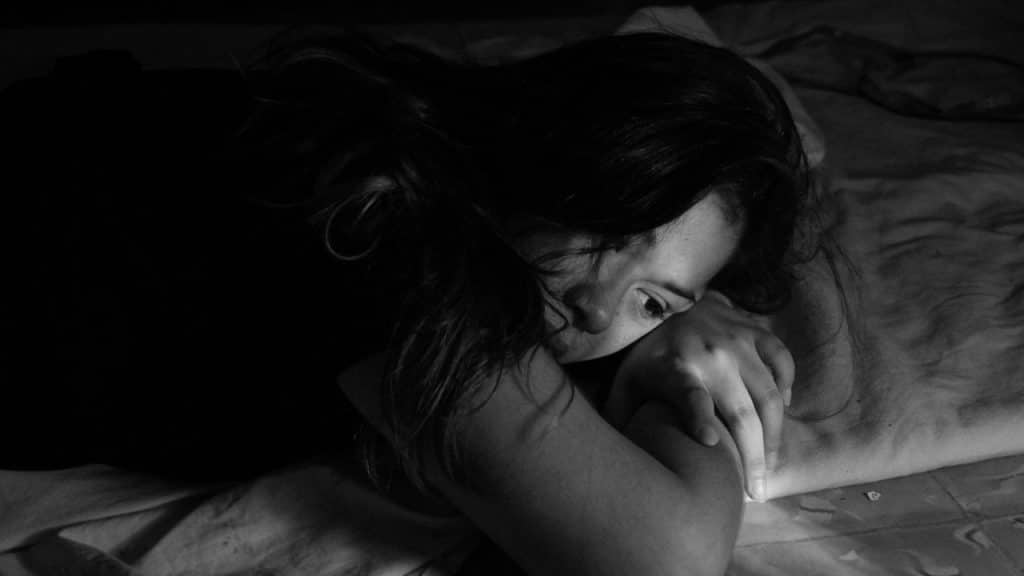 A woman lying on the bed with her head down.