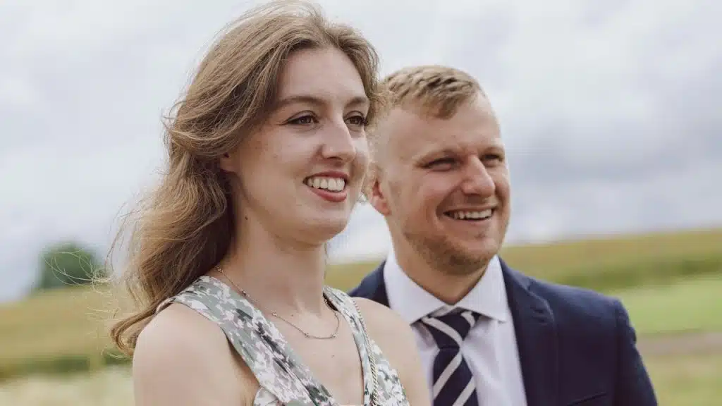 A couple standing next to each other in a field.