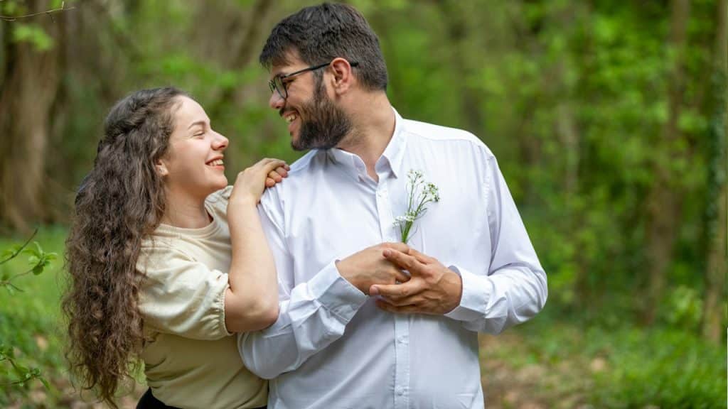 A man and a woman standing in the woods.