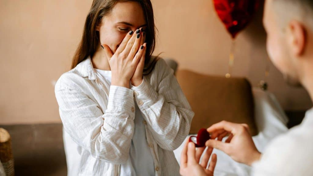 A man proposing with a ring as a woman reacts with surprise and joy.
