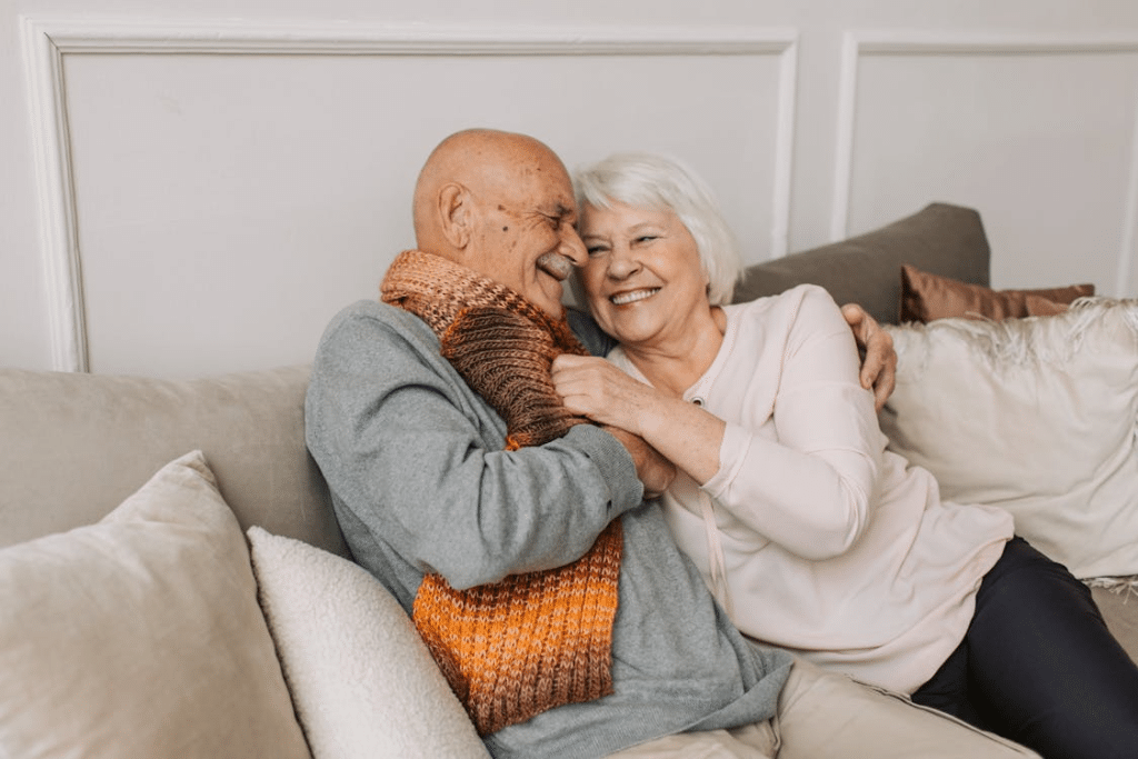 Senior couple on couch smiling and cuddling