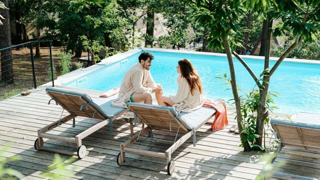 A couple relaxing beside a swimming pool.