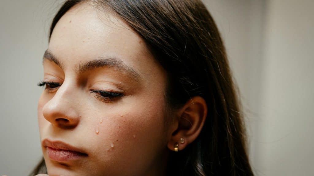 A close-up of a person's face with a tear rolling down their cheek.