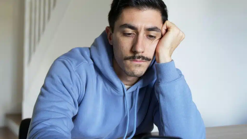 A man in a blue hoodie looking sad.