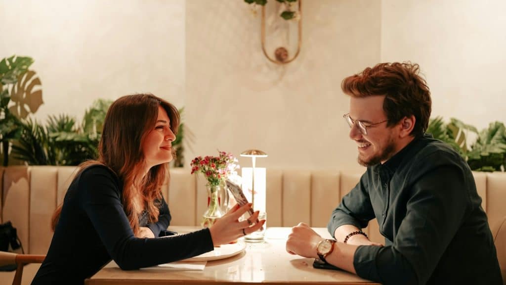 A couple on a date as the woman shows her phone to the man.