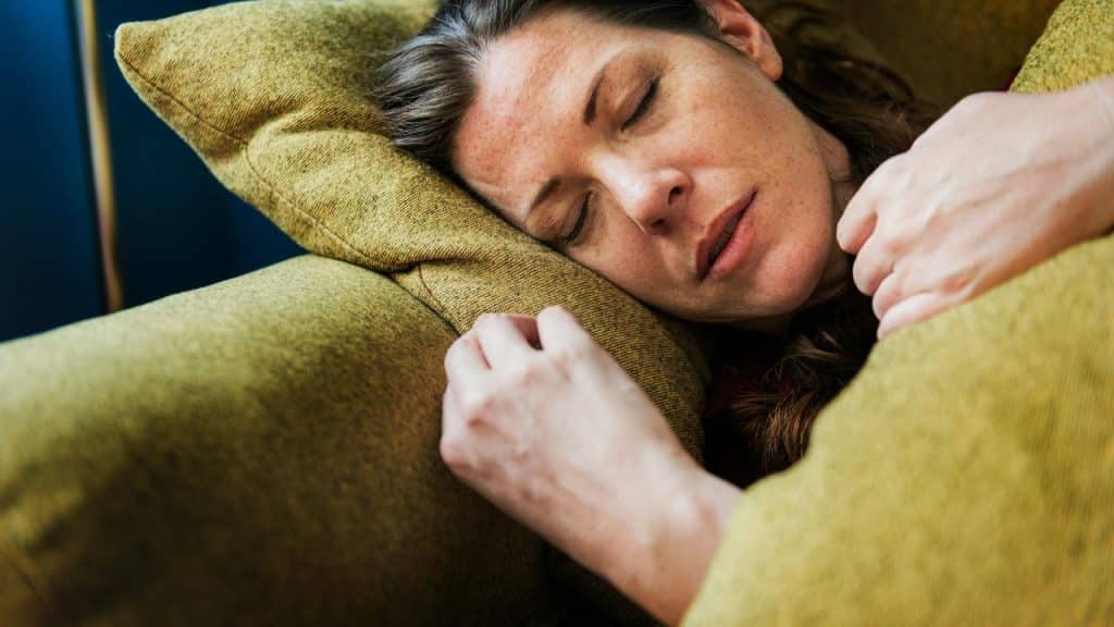 A woman resting with her eyes closed on a couch cushion.
