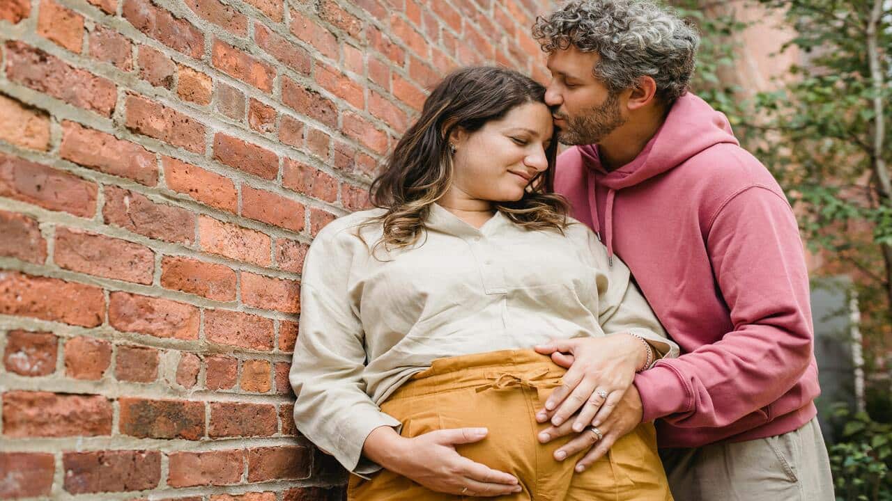 A man hugging and kissing his pregnant wife