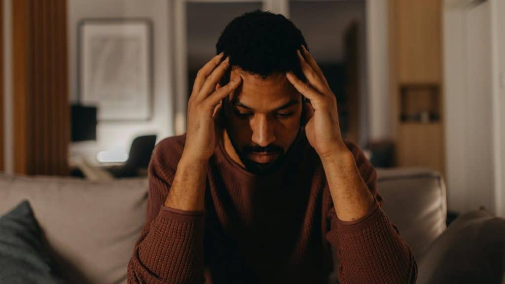 A man holding his head in his hands, looking distressed.