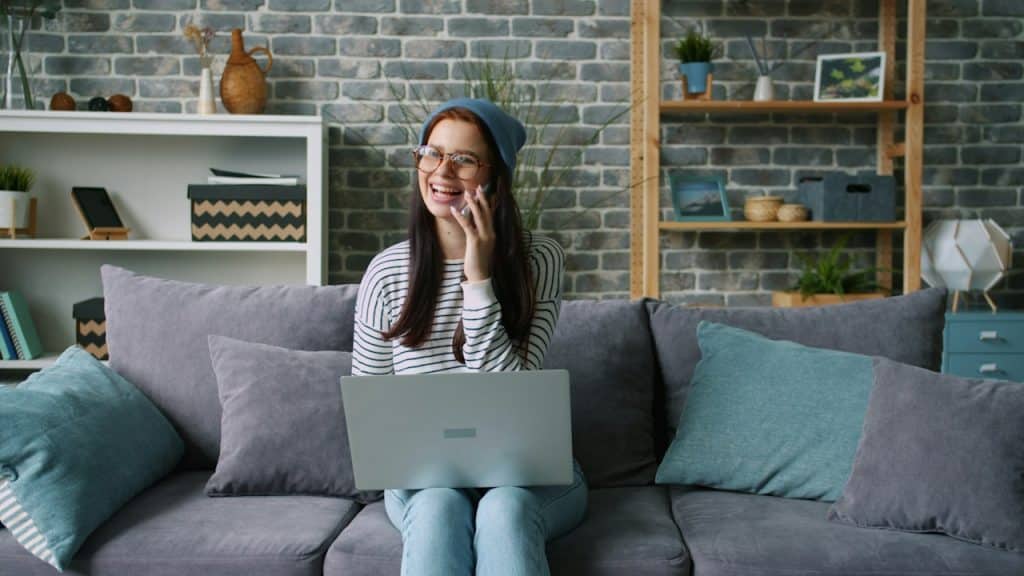A woman-talking-on-phone-with-laptop-on-couch.