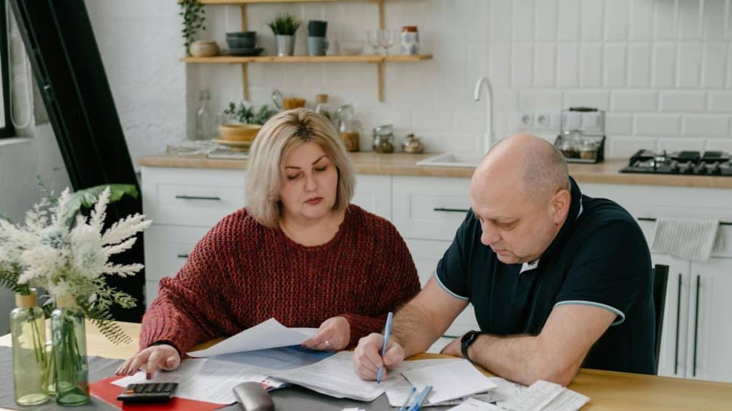 A man and woman doing some paperwork while sitting at a table.