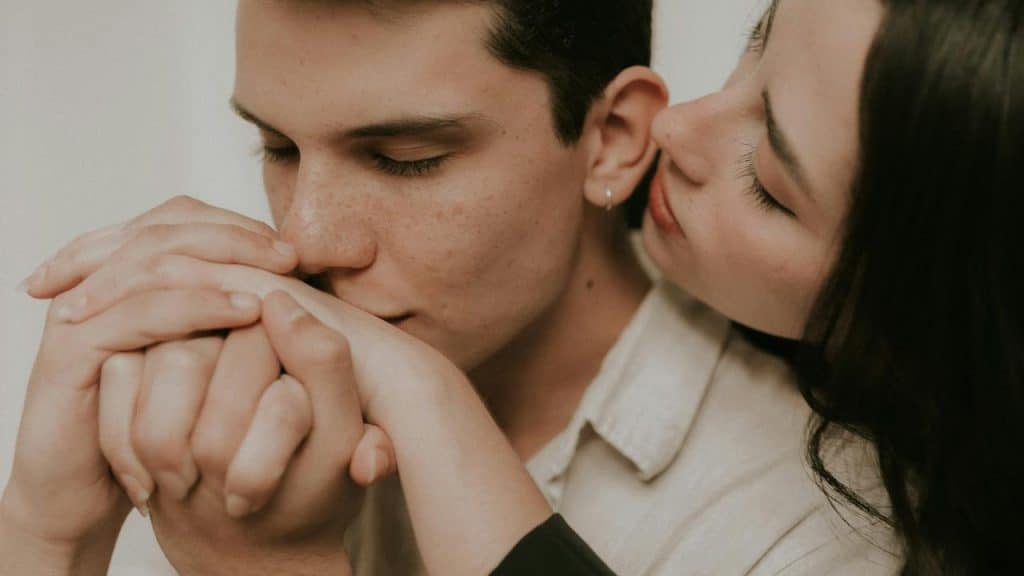 A close-up of a couple holding hands while sharing an intimate moment.
