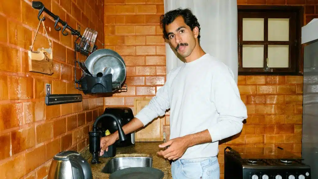 A man washes dishes in his kitchen.
