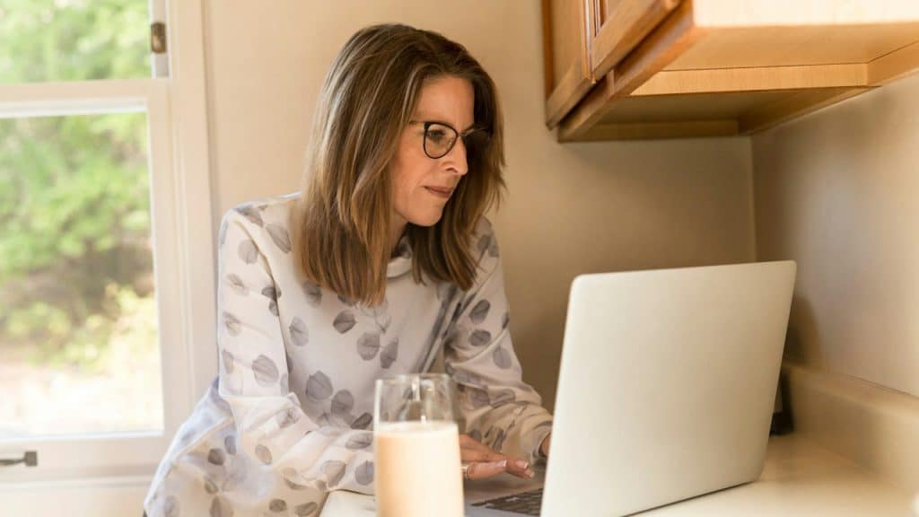 A woman using her MacBook Pro inside a white room.