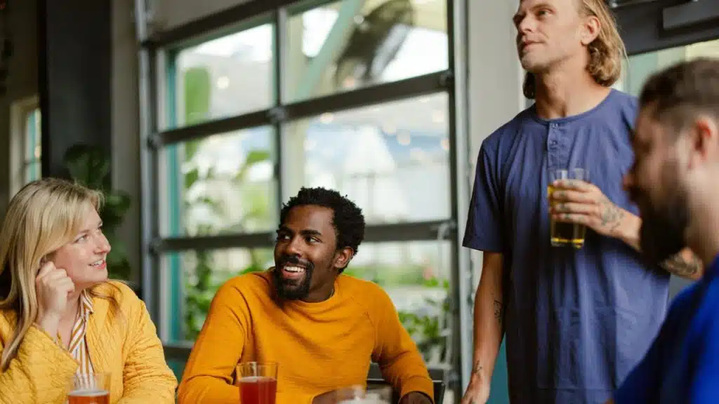 Four people sit at a table together in a restaurant, talking and smiling.