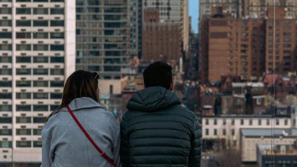 A couple seen from behind looking out over a dense cityscape.