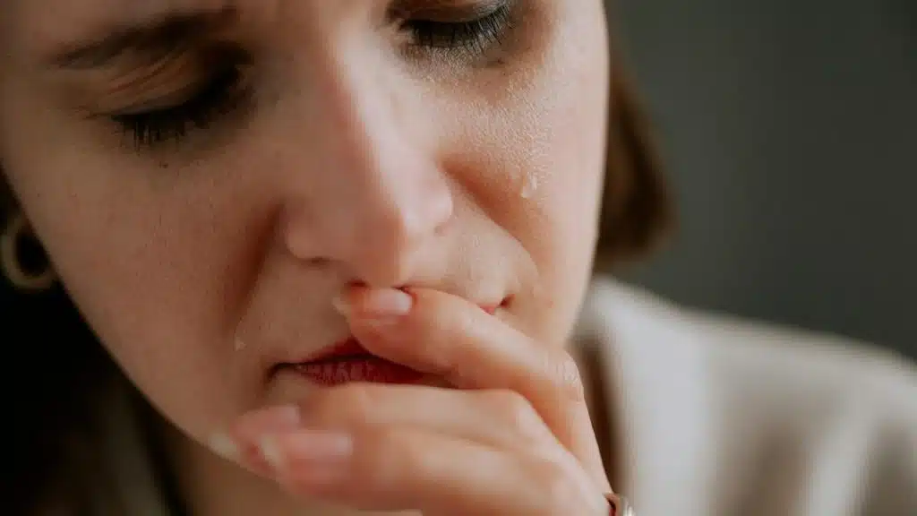 A woman crying with tears falling down her cheek.