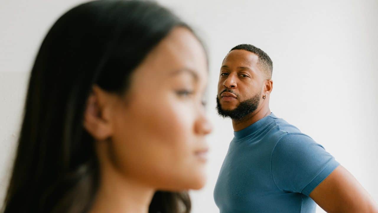 A man in a blue shirt looks toward a woman who is standing out of focus.