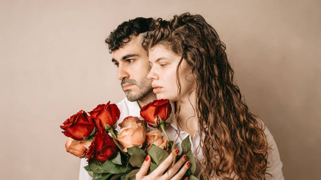 A man and a woman holding roses in their hands.