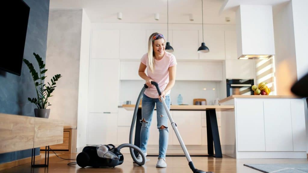 A person vacuuming the floor in a modern kitchen.