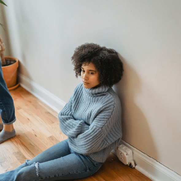 Upset black woman sitting on floor in room
