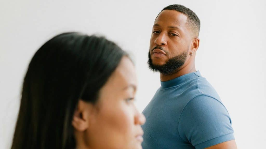 A man in a blue shirt looks over his shoulder toward a woman's blurred profile.