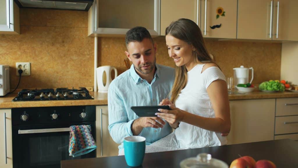 A couple looking at a tablet in the kitchen.