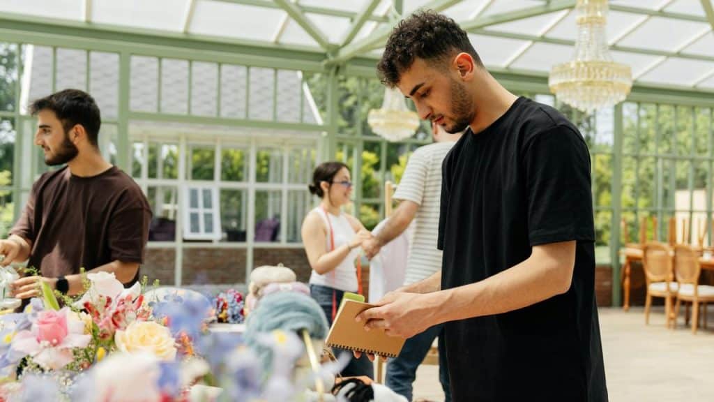 A man writing in a notebook at a market table.