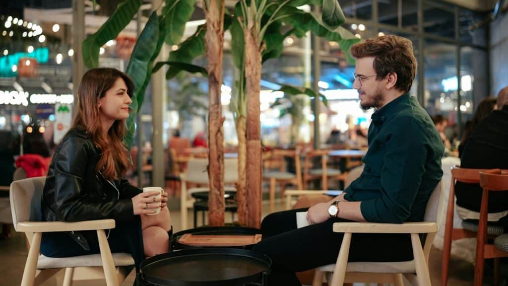 A man and a woman sitting at a table talking.