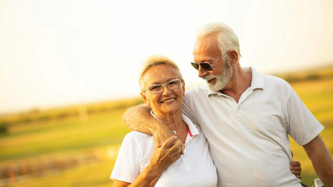 A senior couple embracing on a sunny field.