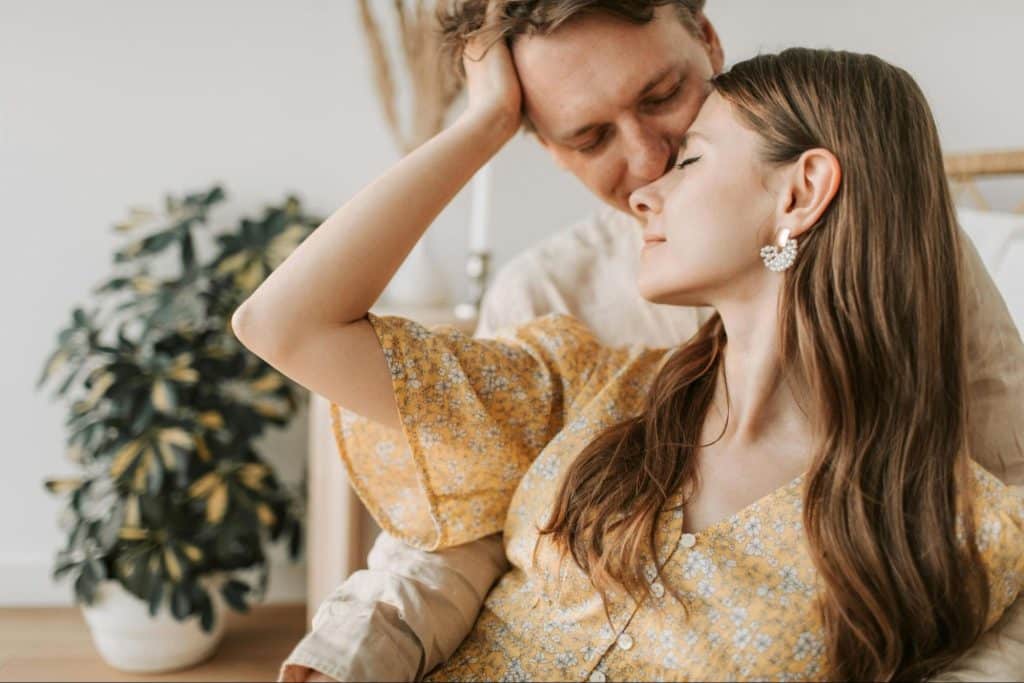 A man kissing woman’s forehead