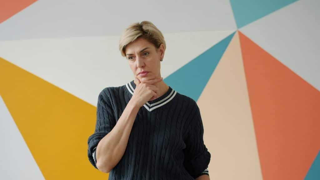 A woman holding her chin in her hand and looking thoughtful.